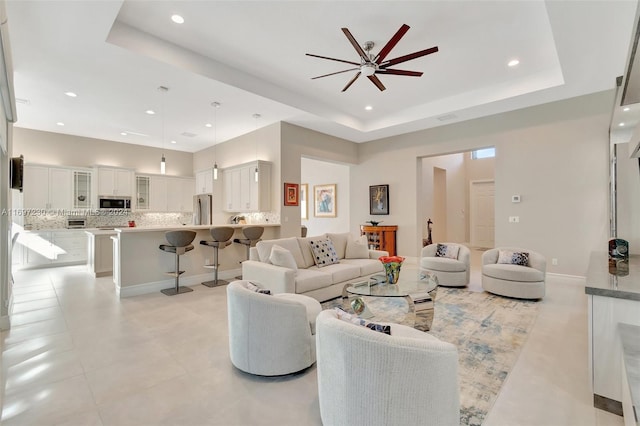 living room with a tray ceiling and ceiling fan