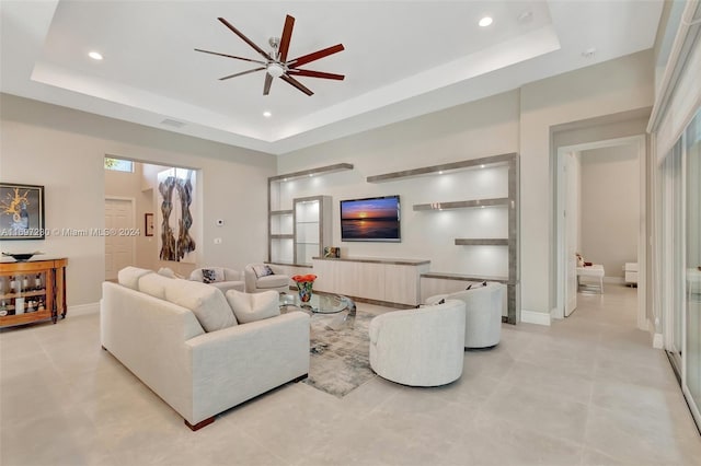 living room featuring ceiling fan and a tray ceiling