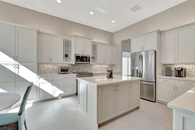 kitchen featuring tasteful backsplash, a center island, white cabinets, and appliances with stainless steel finishes