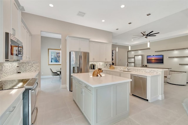 kitchen featuring a kitchen island, sink, kitchen peninsula, and stainless steel appliances