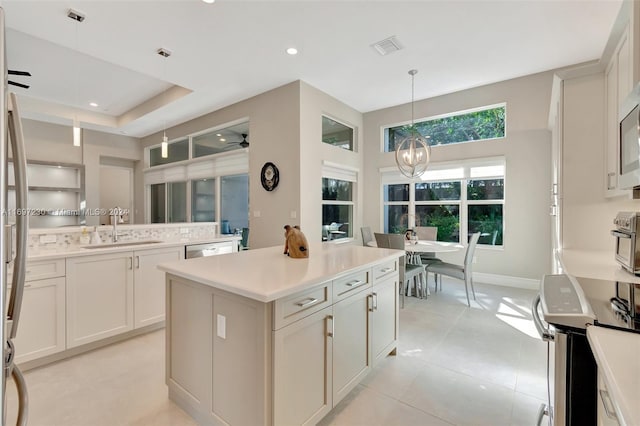 kitchen with a center island, sink, decorative light fixtures, a notable chandelier, and white cabinetry