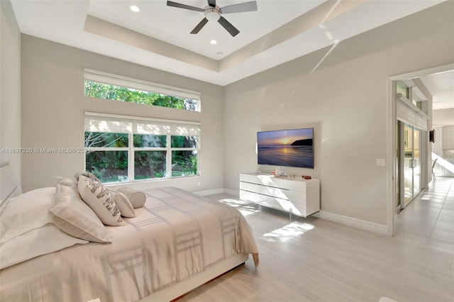 bedroom featuring ceiling fan, light hardwood / wood-style floors, and a raised ceiling