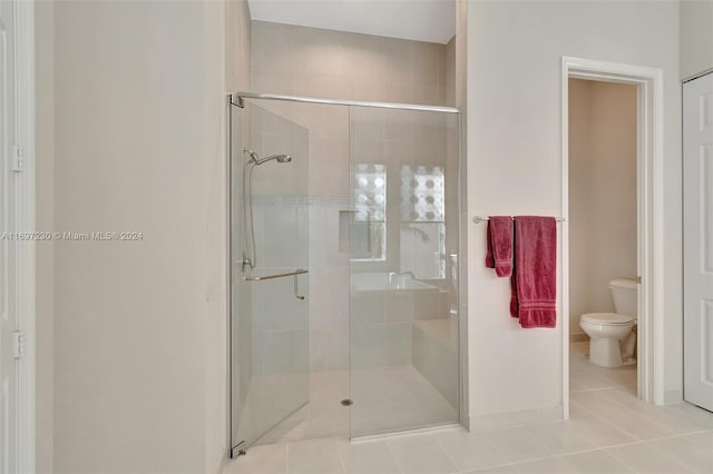 bathroom featuring tile patterned flooring, toilet, and an enclosed shower