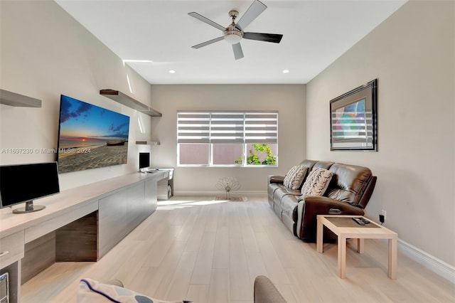 living room featuring built in desk, light hardwood / wood-style floors, and ceiling fan