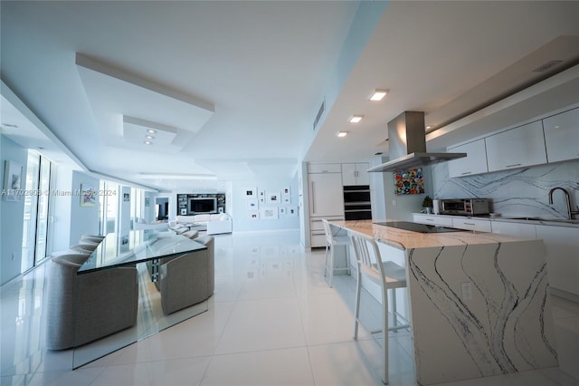 kitchen with light tile patterned floors, backsplash, island range hood, and white cabinetry