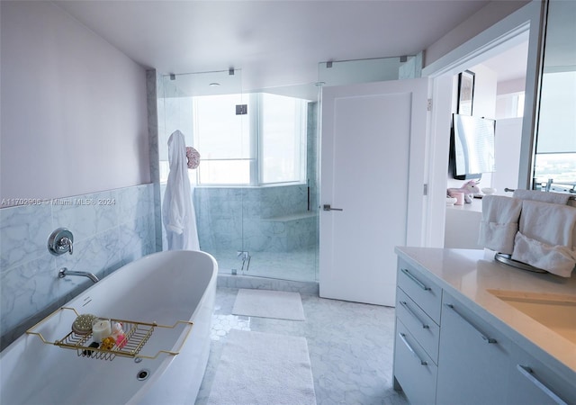 bathroom with shower with separate bathtub, vanity, and tile walls