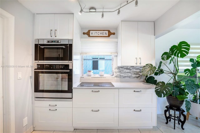 kitchen featuring decorative backsplash, light tile patterned floors, black electric cooktop, double oven, and white cabinetry