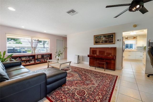 tiled living room featuring ceiling fan and a textured ceiling