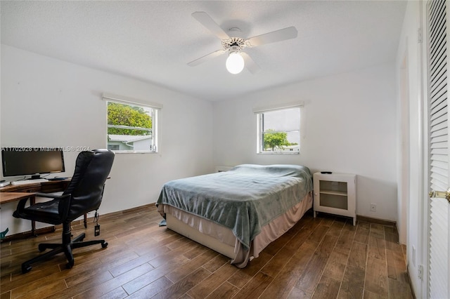 bedroom featuring dark hardwood / wood-style floors, ceiling fan, and multiple windows