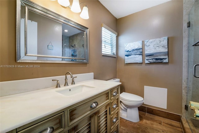 bathroom featuring wood-type flooring, vanity, toilet, and a shower with door