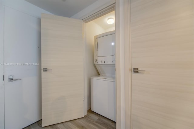 clothes washing area with light hardwood / wood-style floors and stacked washer and dryer