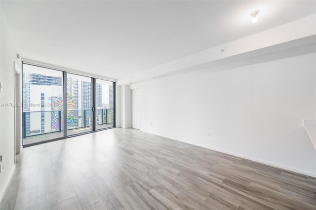 unfurnished room with expansive windows and light hardwood / wood-style flooring