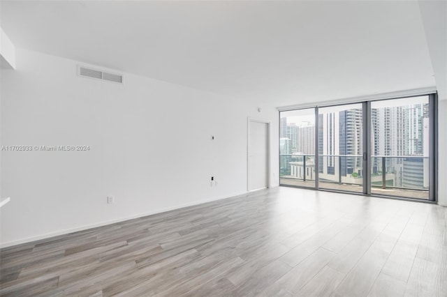 unfurnished room featuring light hardwood / wood-style floors and floor to ceiling windows