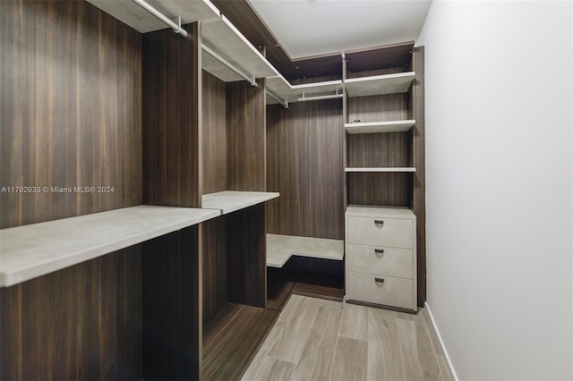 walk in closet with light hardwood / wood-style flooring