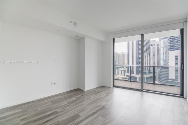 unfurnished room with light hardwood / wood-style flooring and a wall of windows