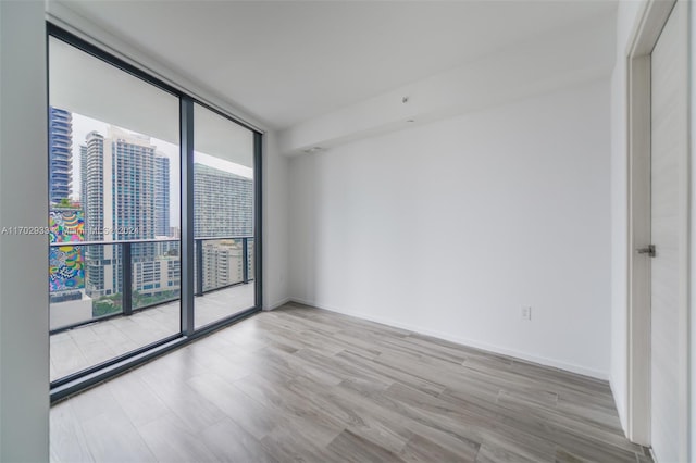 unfurnished room with light hardwood / wood-style flooring and floor to ceiling windows