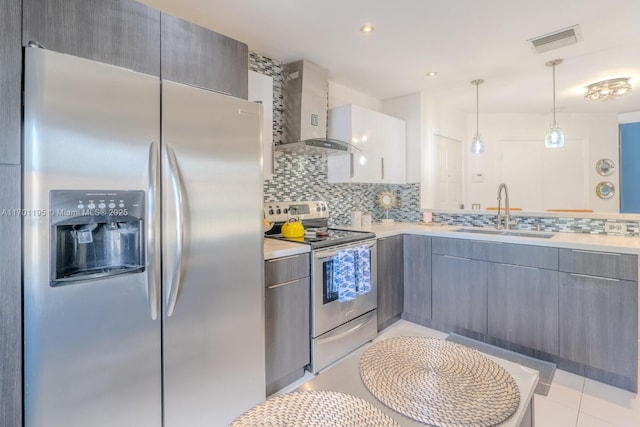 kitchen featuring pendant lighting, backsplash, sink, wall chimney exhaust hood, and appliances with stainless steel finishes