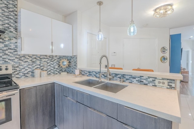 kitchen featuring white cabinets, sink, electric range, gray cabinets, and decorative light fixtures