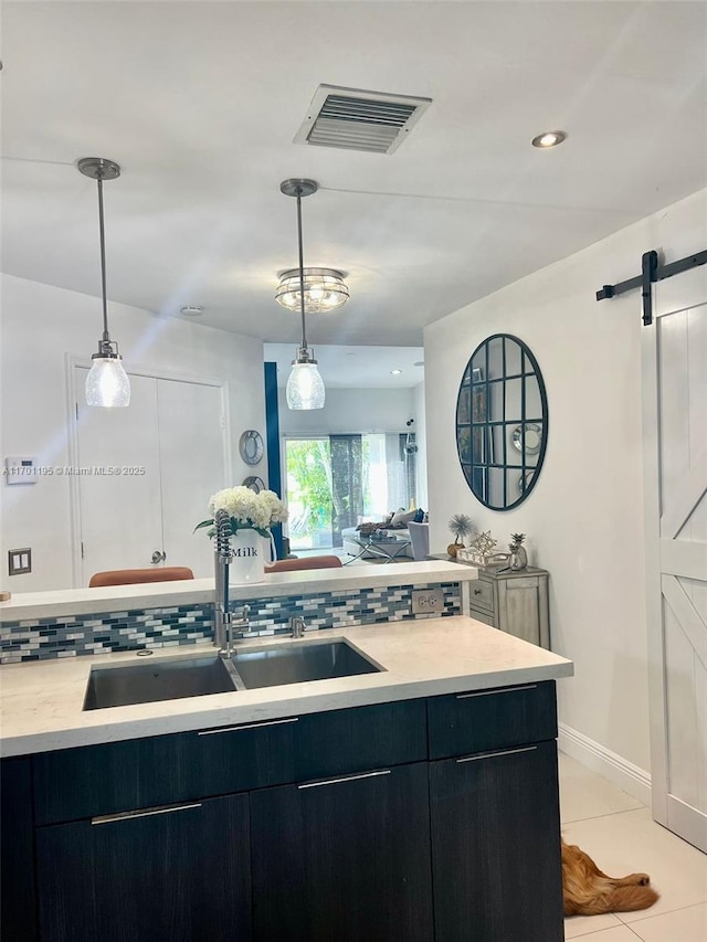 kitchen with decorative backsplash, light tile patterned floors, a barn door, and sink