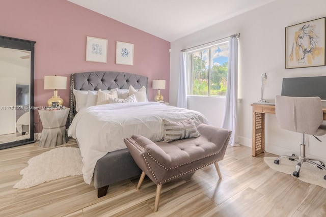 bedroom with light wood-type flooring and vaulted ceiling