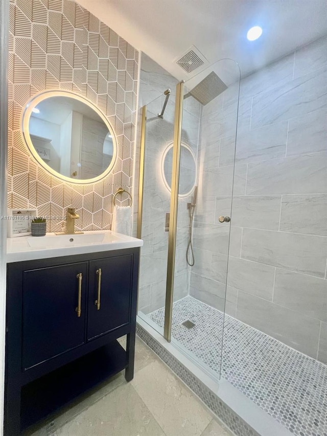 bathroom featuring a tile shower, vanity, and tile walls