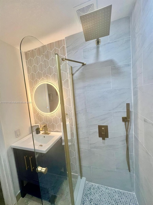 bathroom with a tile shower and vanity