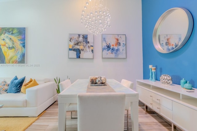 dining area with light wood-type flooring and a notable chandelier