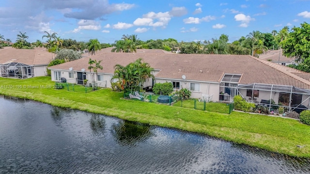 back of house with a lanai, a lawn, and a water view