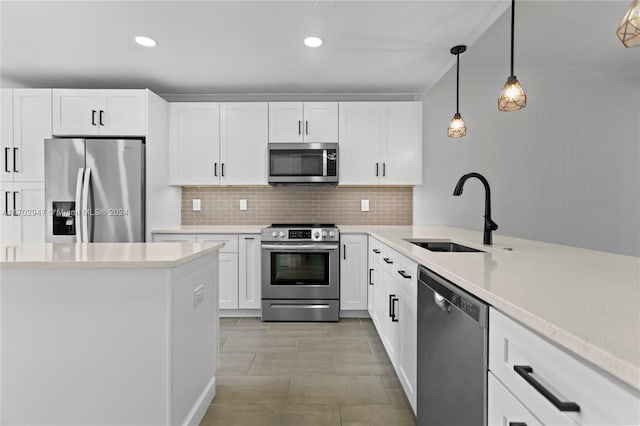 kitchen with pendant lighting, backsplash, white cabinets, sink, and appliances with stainless steel finishes