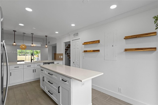 kitchen featuring kitchen peninsula, sink, white cabinets, a kitchen island, and hanging light fixtures