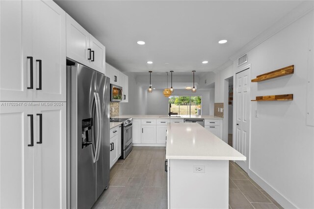 kitchen featuring white cabinetry, sink, hanging light fixtures, stainless steel appliances, and kitchen peninsula