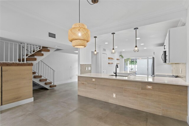 kitchen with pendant lighting, backsplash, white cabinetry, and concrete floors