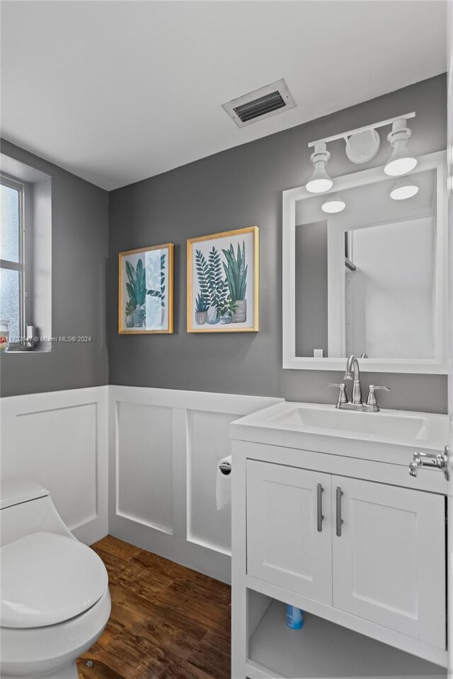 bathroom with toilet, vanity, and hardwood / wood-style flooring