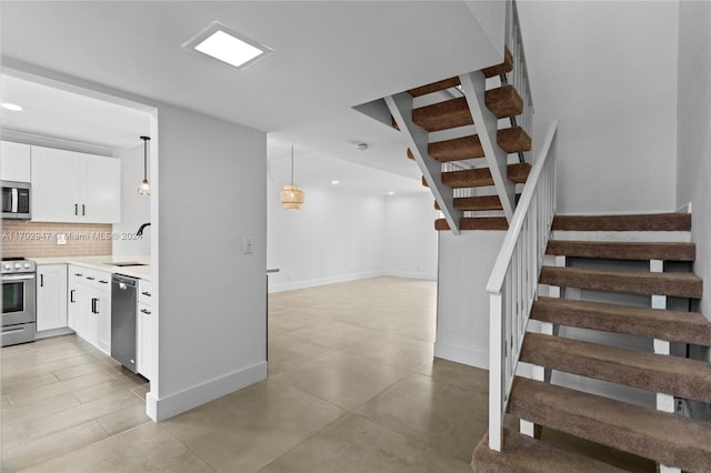 kitchen featuring decorative light fixtures, white cabinetry, backsplash, and appliances with stainless steel finishes