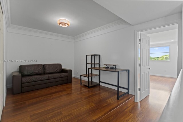 sitting room with ornamental molding and dark wood-type flooring