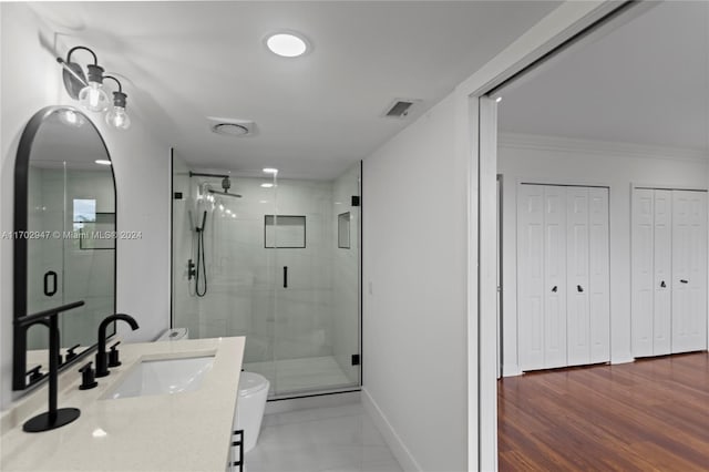 bathroom featuring ornamental molding, vanity, hardwood / wood-style floors, toilet, and a shower with shower door