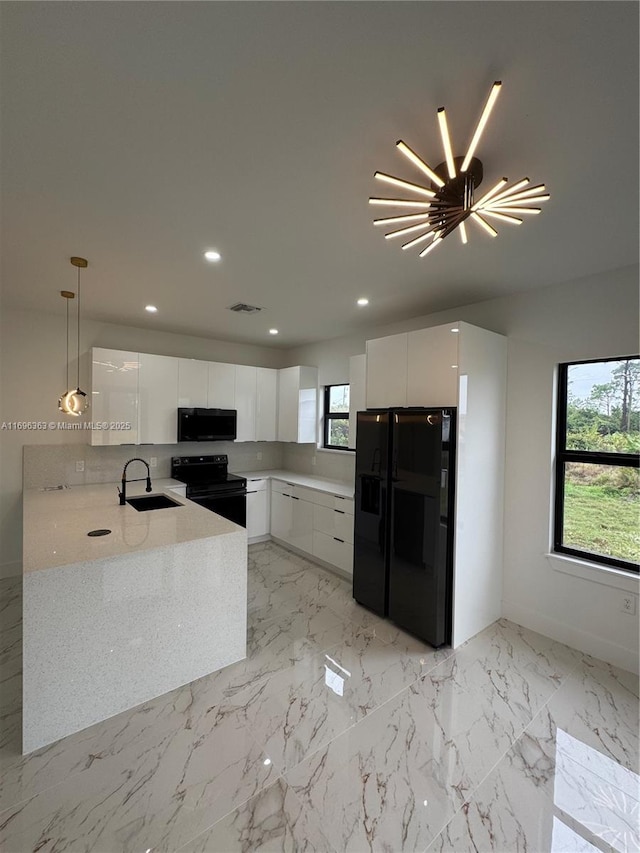 kitchen with sink, white cabinetry, black appliances, decorative light fixtures, and kitchen peninsula