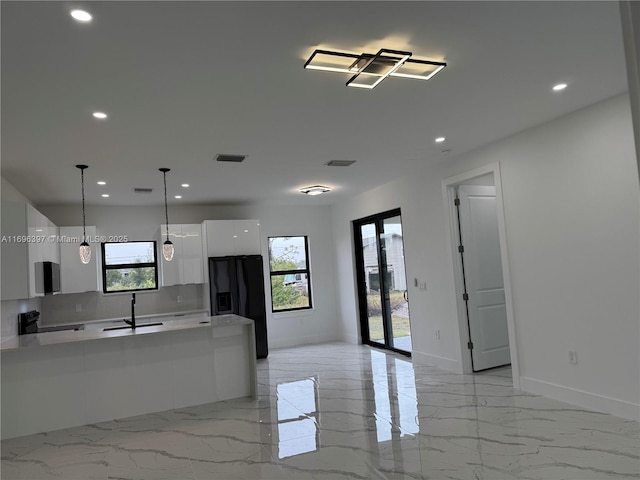 kitchen with plenty of natural light, white cabinets, black refrigerator with ice dispenser, and decorative light fixtures