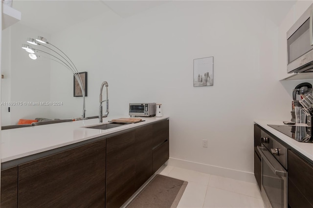 kitchen featuring black electric stovetop, dark brown cabinets, light tile patterned flooring, and sink