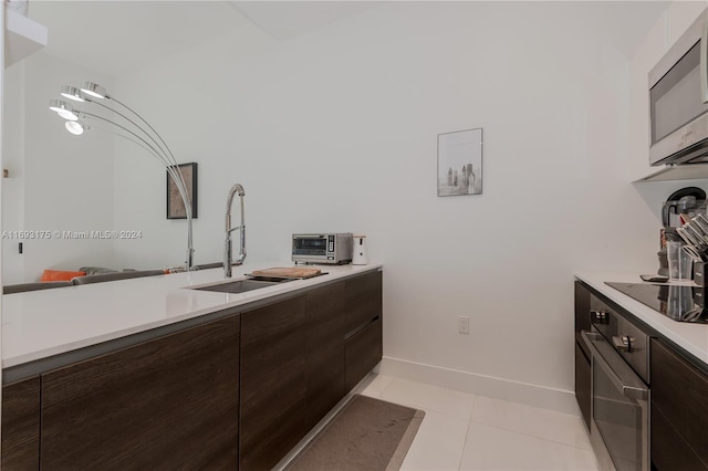 301 Altara Ave Unit 305, Coral Gables, FL 33146 - kitchen with stainless steel appliances, a sink, dark brown cabinetry, and light countertops