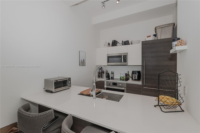 301 Altara Ave Unit 305, Coral Gables, FL 33146 - kitchen with stainless steel microwave, a breakfast bar, a peninsula, decorative backsplash, and oven
