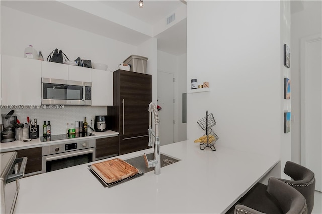 kitchen featuring sink, appliances with stainless steel finishes, tasteful backsplash, white cabinetry, and dark brown cabinetry