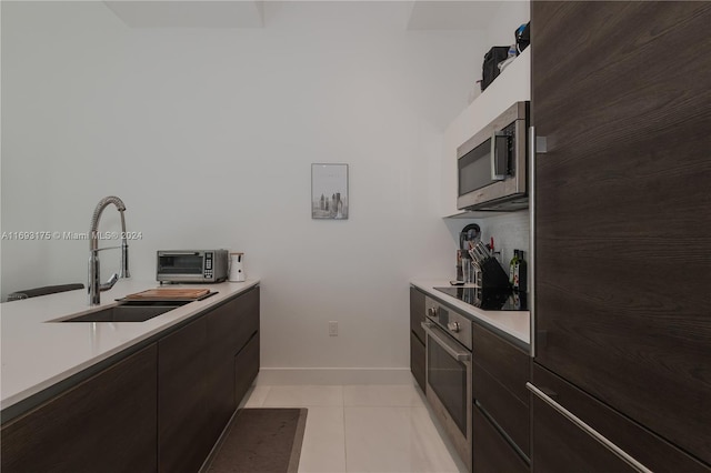 kitchen with light tile patterned floors, dark brown cabinetry, stainless steel appliances, and sink