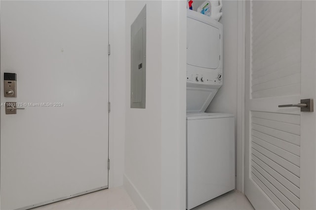 clothes washing area with electric panel and stacked washing maching and dryer