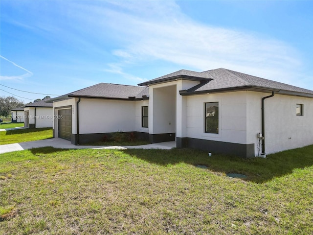 view of front of property with an attached garage, a front yard, and stucco siding