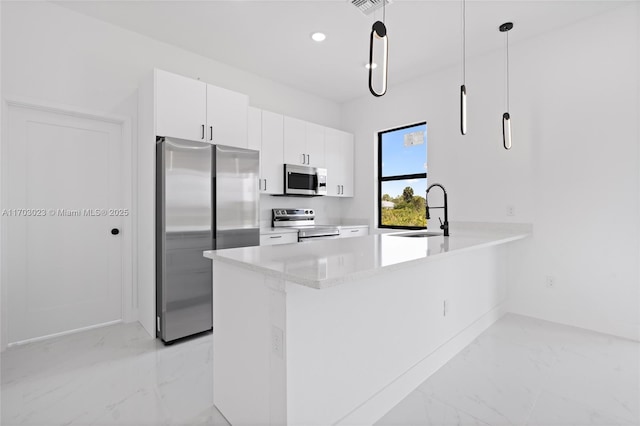 kitchen featuring white cabinets, appliances with stainless steel finishes, light countertops, pendant lighting, and a sink