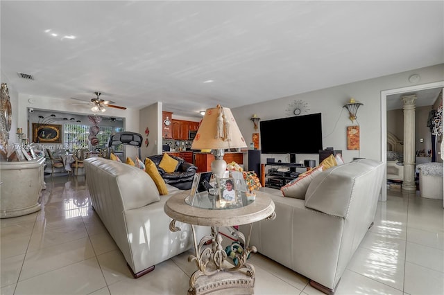 tiled living room with ceiling fan and ornate columns