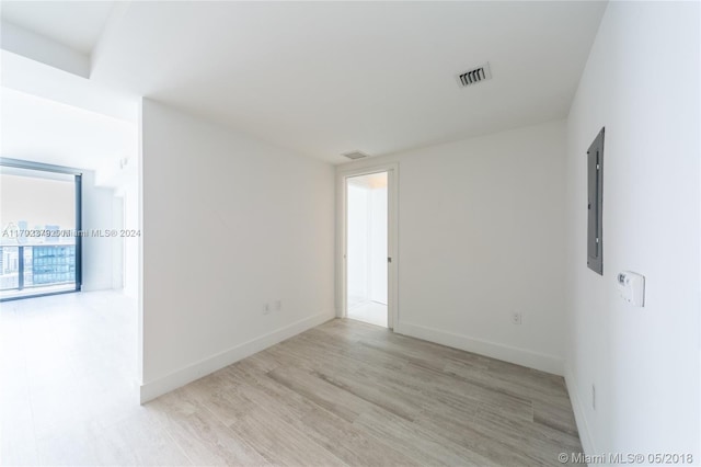 empty room with electric panel and light hardwood / wood-style flooring