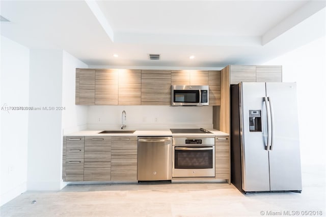 kitchen featuring a tray ceiling, sink, and stainless steel appliances