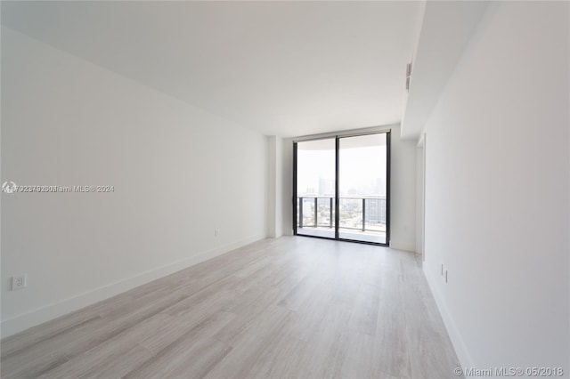 spare room featuring a wall of windows and light hardwood / wood-style flooring